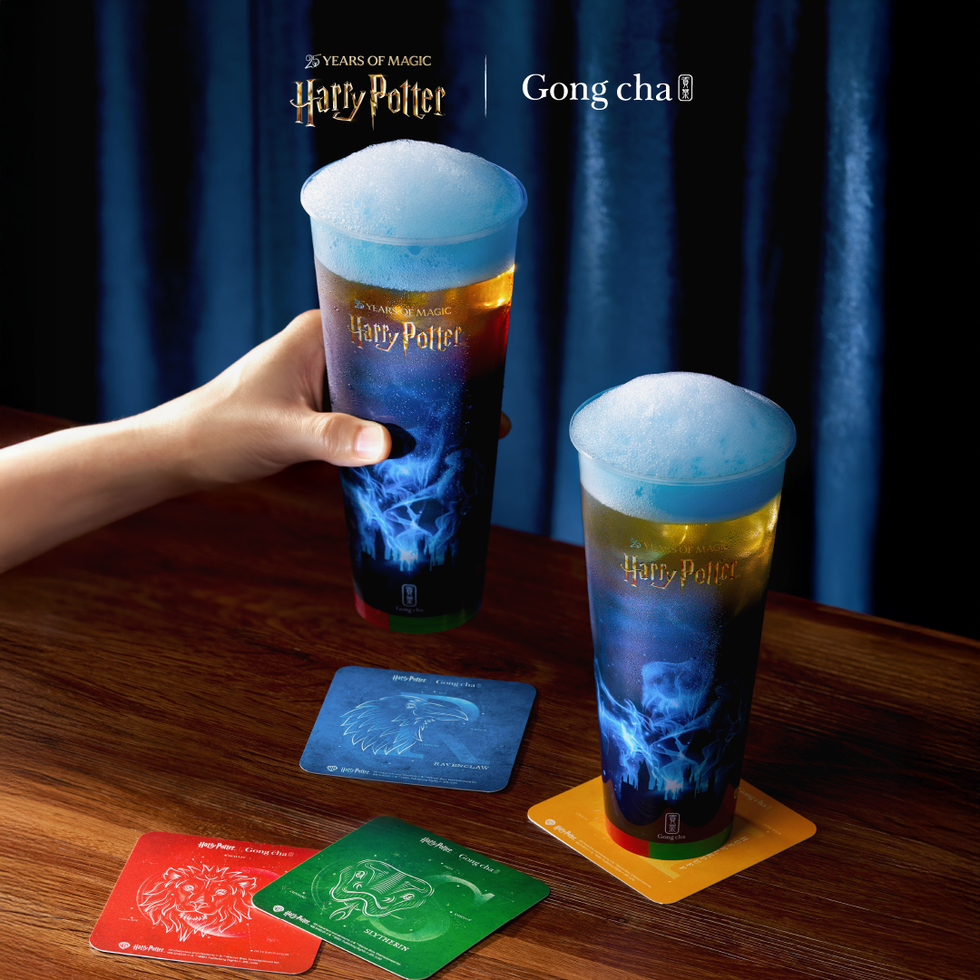 Two colorful drinks with foam, Harry Potter-themed coasters on a wooden table.