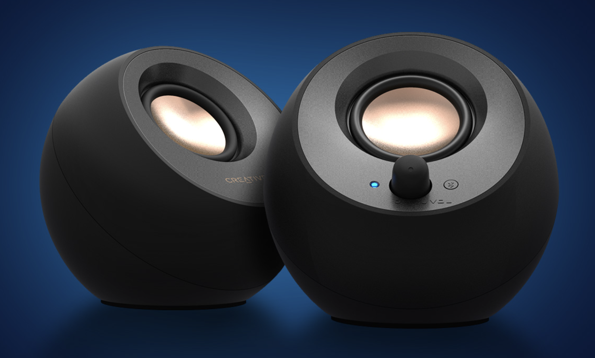 The black Creative Pebble V3 speakers in front of a navy blue gradient background.