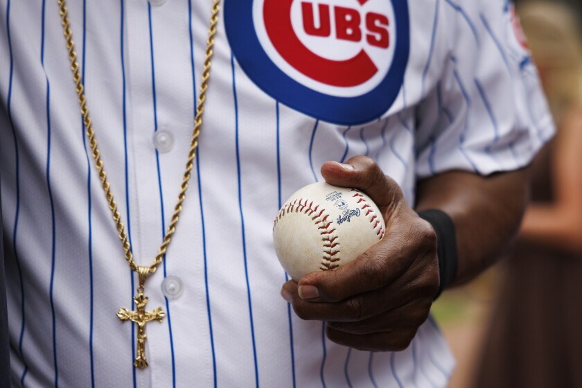 Mr. T wears a gold crucifix necklace and holds a baseball as he warms up for his ceremonial pitch.