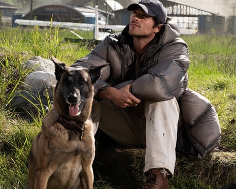 Jacob Elordi as Hig crouches beside his dog Jasper in a grassy field