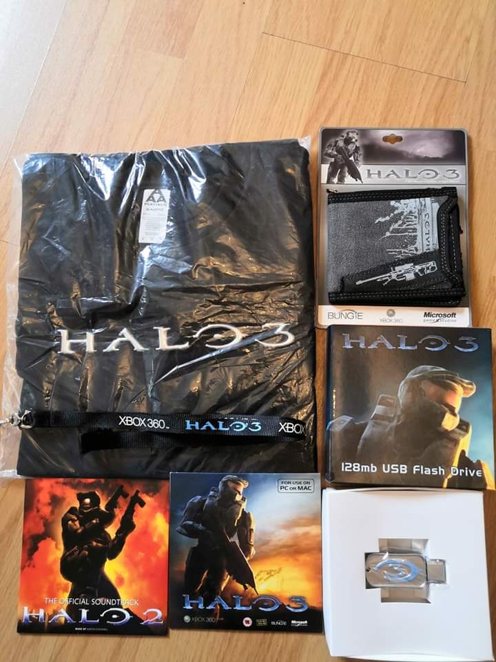 A collection of Halo 3 items including a lanyard, a t-shirt, a wallet, a 128mb Flash Drive, a Halo 2 soundtrack, and a copy of Halo 3 demo disk.