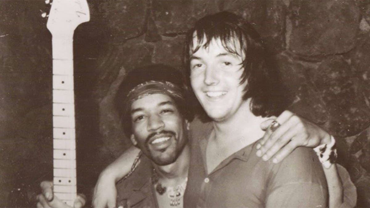 Eric Barrett being embraced by Jimi Hendrix who is holding a guitar.