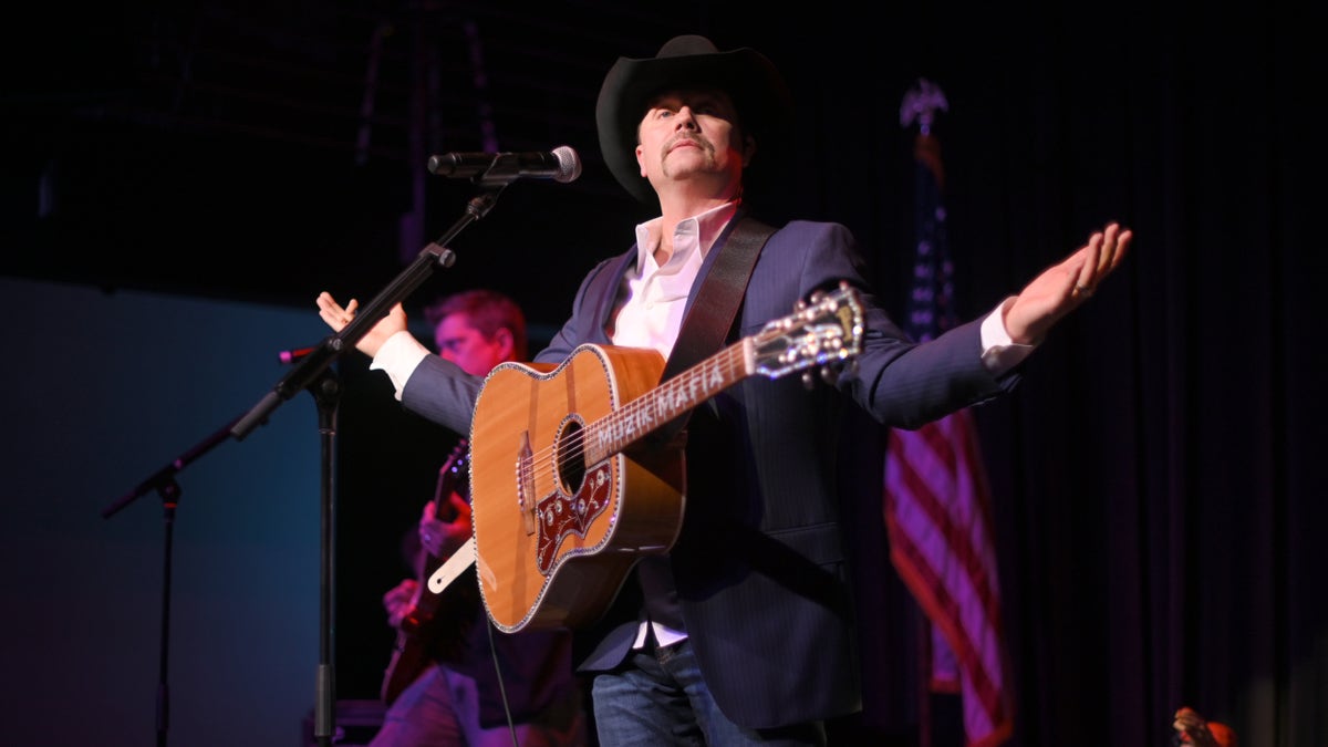 John Rich holds a guitar on stage during concert