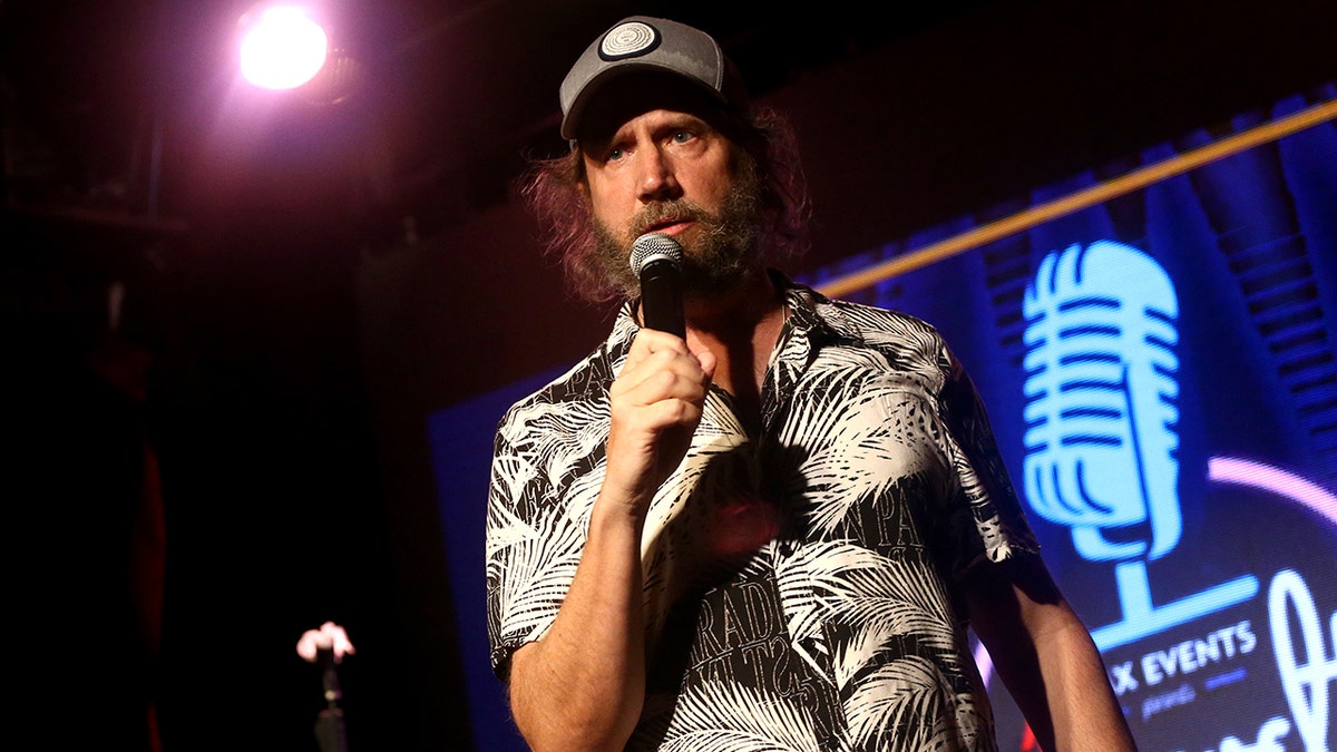 Jamie Kennedy holds a microphone onstage