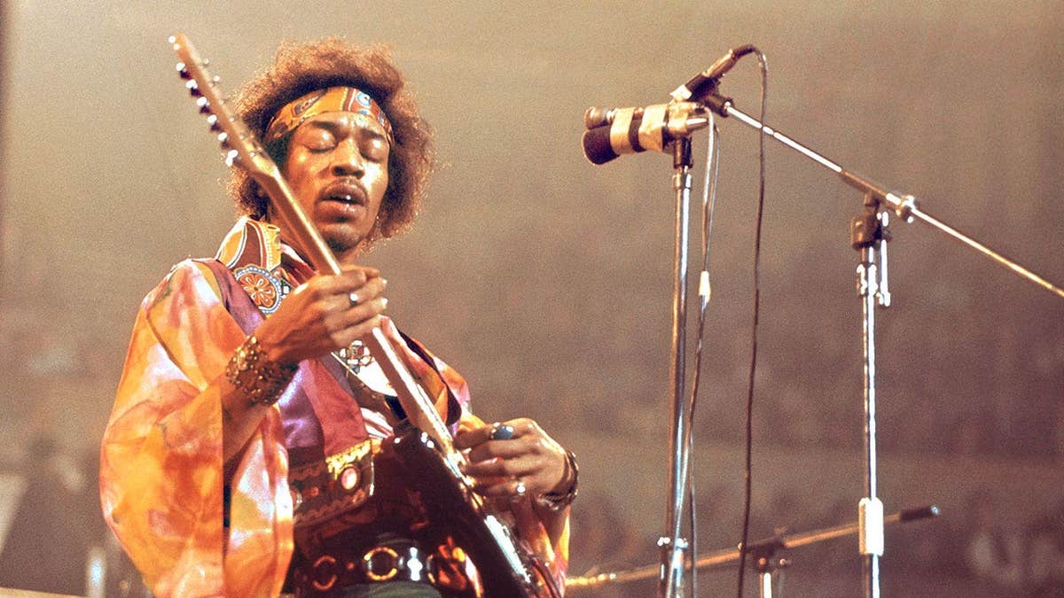 Jimi Hendrix performing on stage with his eyes closed.