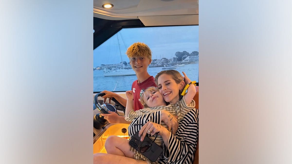 Kelly Osbourne smiles while holding her 3-year-old son, Sidney, aboard a boat.