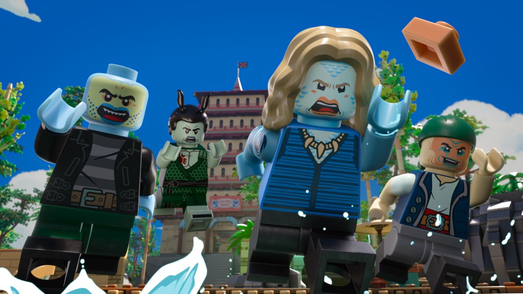 "Four LEGO pirate and villain minifigures run forward outdoors, with water splashing in front of them, tropical palm trees, and a large building in the background under a blue sky. One figure throws a LEGO brick."