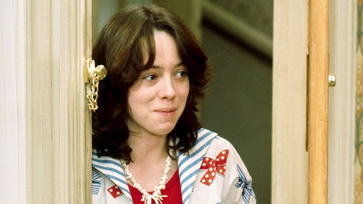 Mackenzie Phillips stands as Julie Cooper in a studio portrait.