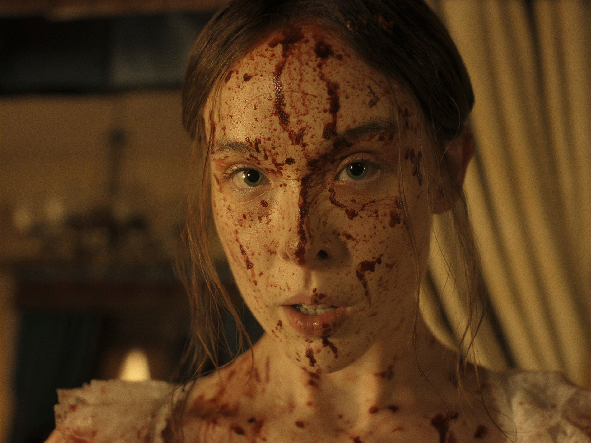 &Quot;A Young Woman With Long Hair, Dressed In Light Clothing, Has Her Face And Upper Chest Covered In Blood, Standing Indoors With Dim Warm Lighting And Blurred Curtains And Furnishings In The Background.&Quot;