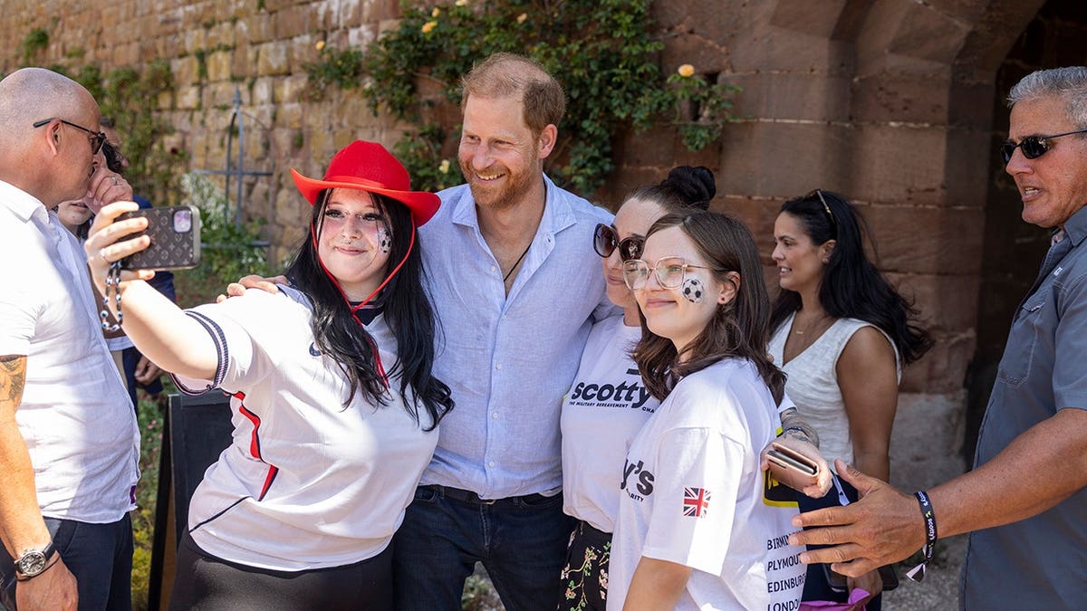 Prince Harry poses for a selfie with well-wishers at Maxstoke Castle.