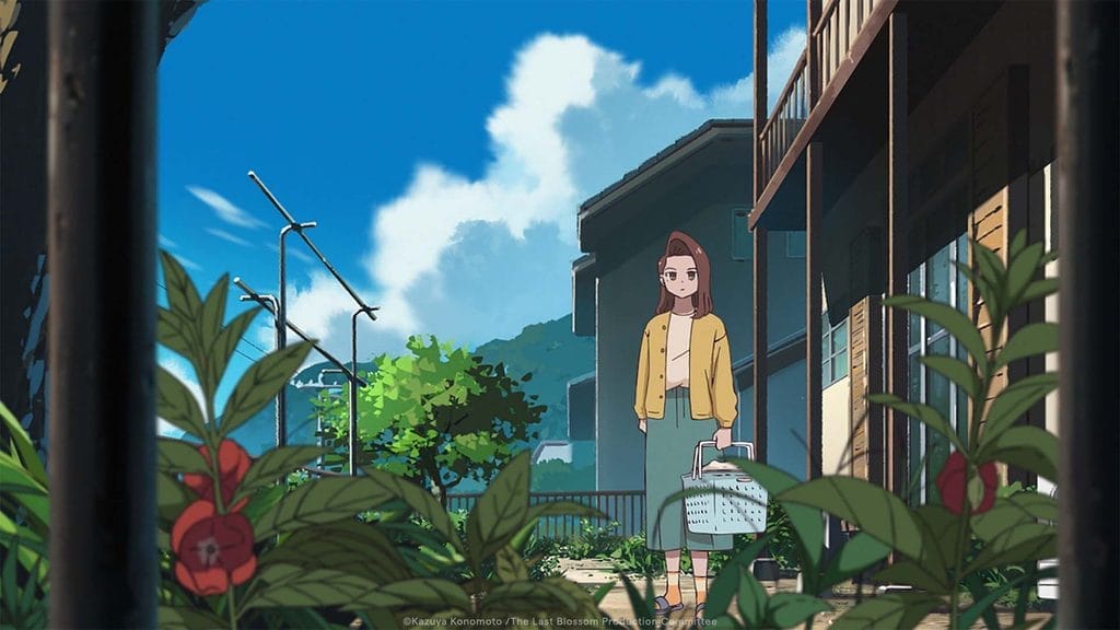 Still from The Last Blossom that depicts a brown-haired woman in a yellow jacket holding a basket, as she looks over a few scraggly flowers growing behind an apartment building.