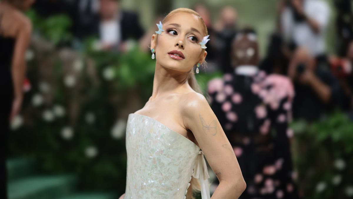 Ariana Grande standing in a black and white gown at the Met Gala in New York City.