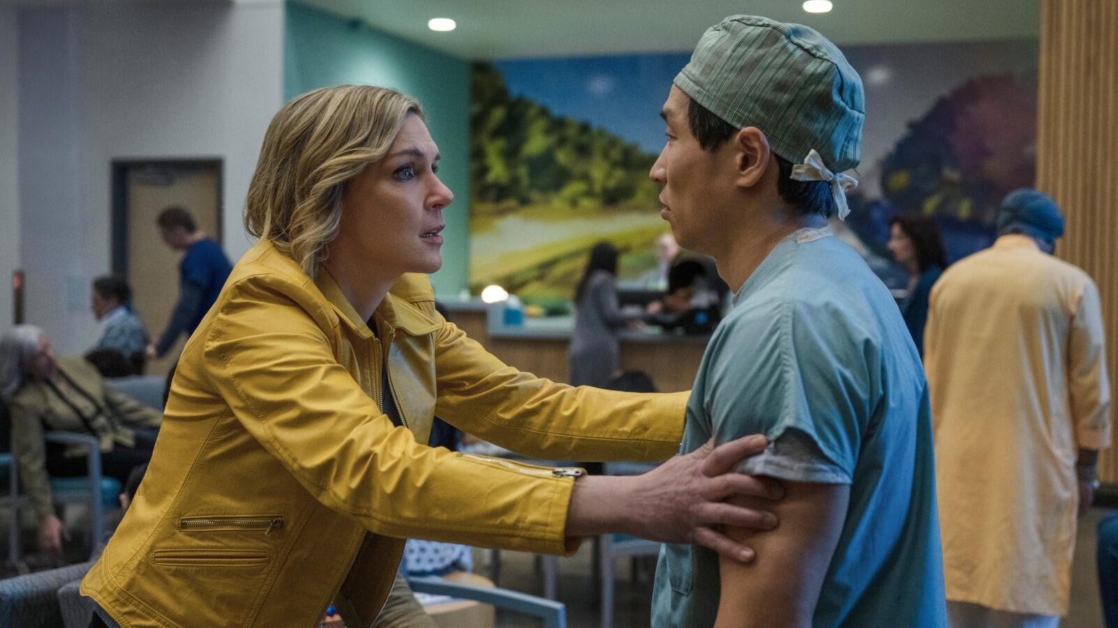 A still from Pluribus featuring Seehorn's character grabbing the arms of a medical professional who is wearing a scrub cap.