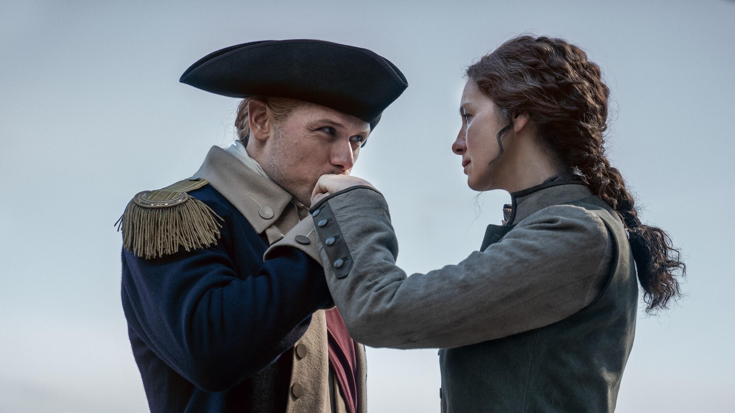 man with colonial hat kisses woman's hand