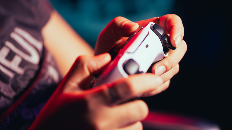a person holding and using a PlayStation 5 controller in their hands