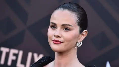AFP via Getty Images Head and shoulders image of Selena Gomez in sparkly black top and leaf shaped earring as she poses for pictures during a premiere of Marty, Life is Short in May 2026.