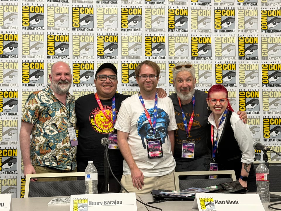 Graeme McMillan, Henry Barajas, Steve Morris, Matt Kindt, and Kelly Sue Deconnick standing on the stage in front of the SDCC logo step and repeat.