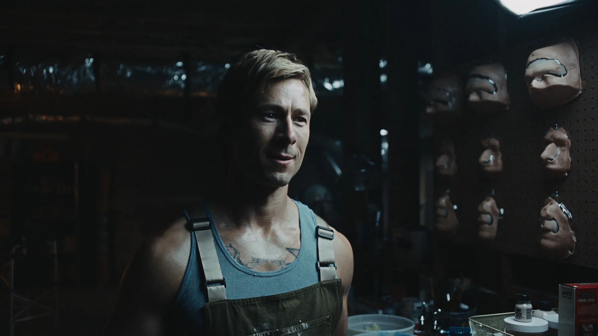 Russ Holliday (Glen Powell) in a room filled with prosthetics.