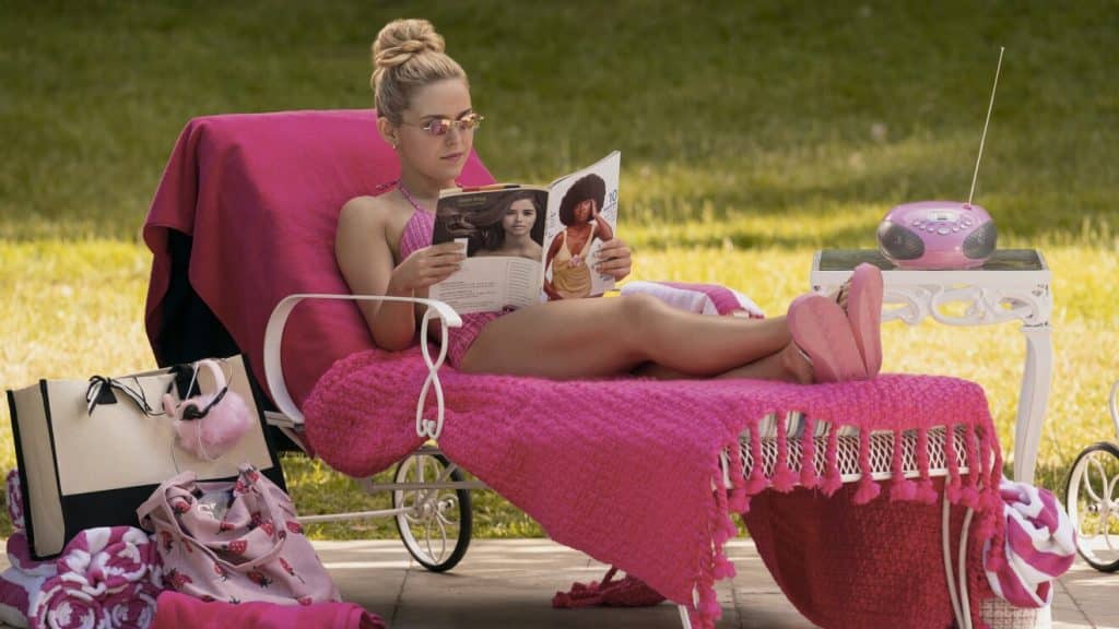 elle woods sitting with her dog on a beach lawn chair