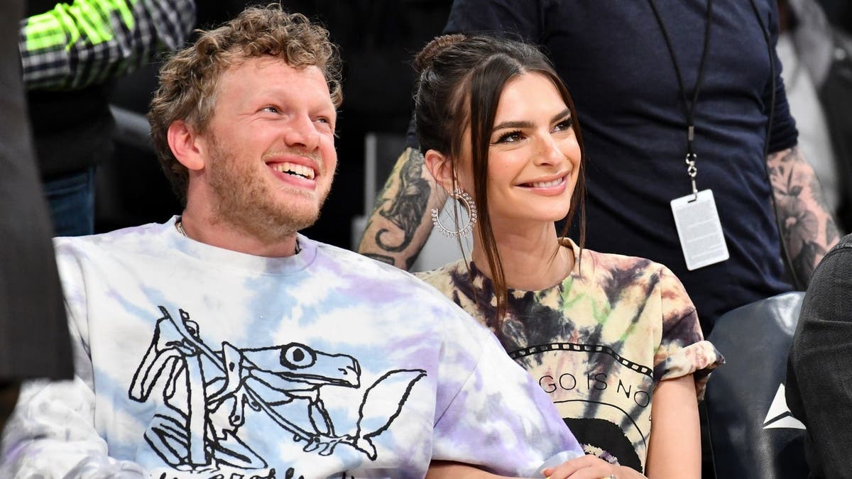 Emily Ratajkowski and Sebastian Bear-McClard standing courtside at a basketball game.