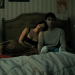 A screenshot of Michael Johnston as Bear and Inde Navarrette as Nikki lying in a bed in Obsession