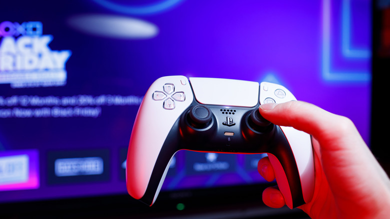 Holding the DualSense in front of a TV showing the PS5's home page