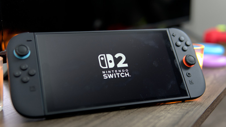 A Nintendo Switch 2 on a wooden surface with a TV in the background.