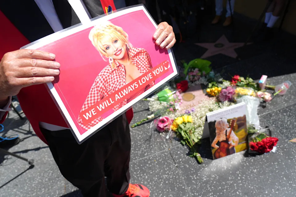 Actor Gregg Donovan holds a poster over Dolly Parton's star on the Hollywood Walk of Fame on Tuesday, Aug. 25, 2026, in Los Angeles. (AP Photo/Chris Pizzello)