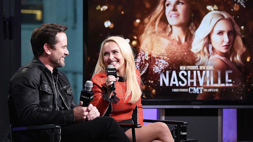 Charles Esten and Hayden Panettiere at a press event with a "Nashville" poster behind them