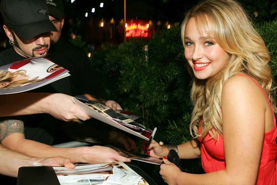 Hayden Panettiere during Teen Vogue Young Hollywood Party on the red carpet signing autographs. She is wearing a red dress and smiling at the camera