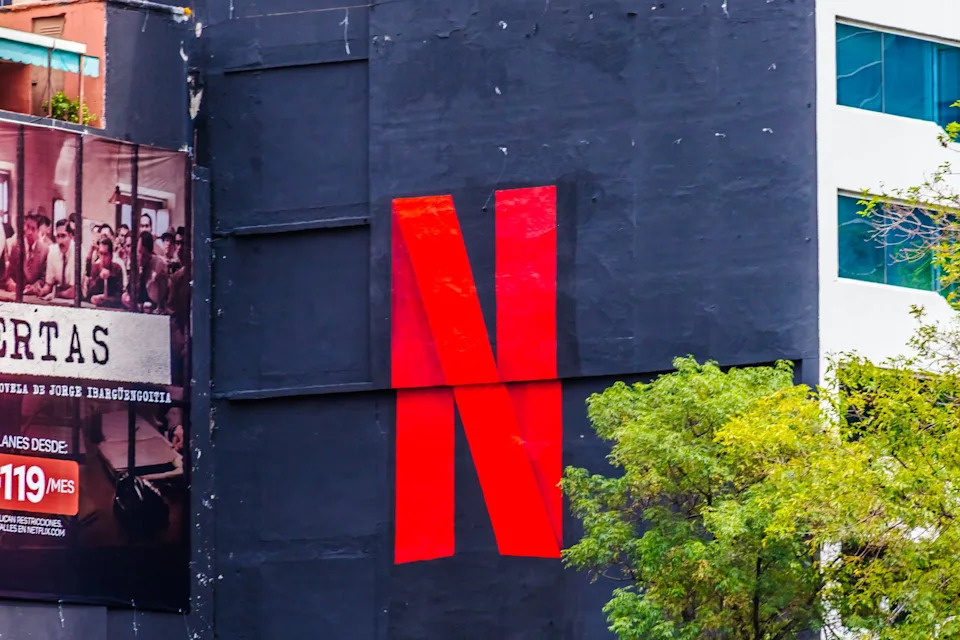 Large red Netflix logo on a black building wall with trees in the foreground