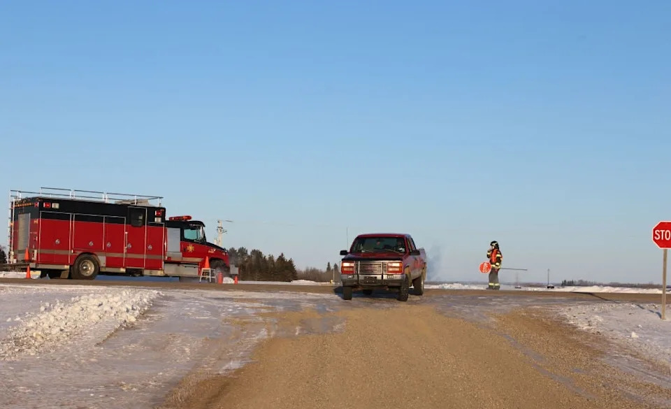 Fire truck and firefighter blocking snowy rural road, with truck stopped at intersection