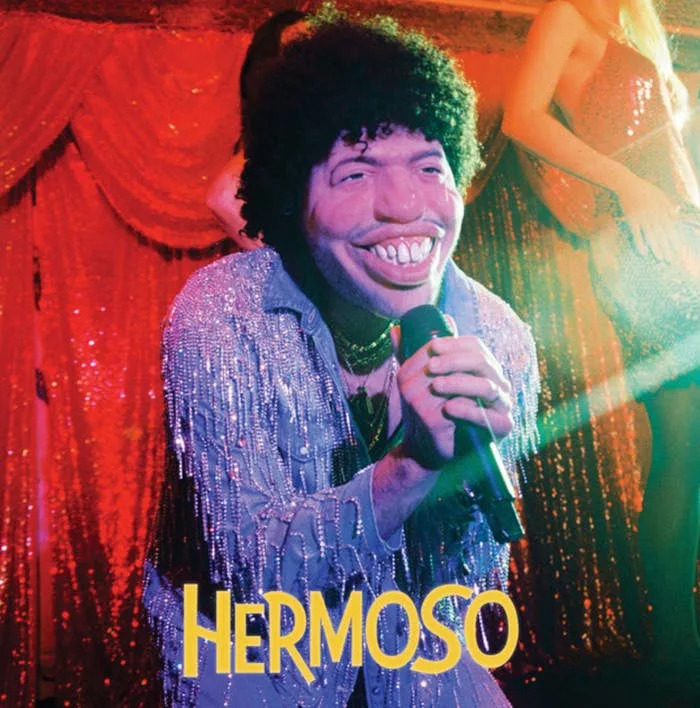 Benny wearing a large, exaggerated mask and sparkly outfit on an album cover