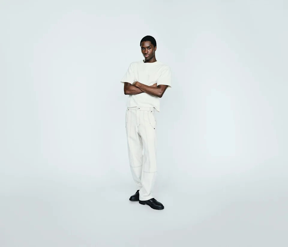 A person in casual clothing stands confidently with arms crossed against a plain background.