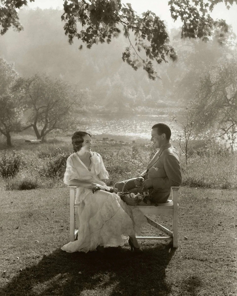 Actor Fay Wray, left, sits with her husband, writer John Monk Saunders, on a wooden bench near a lake.  (Edward Steichen/Conde Nast via Getty Images)