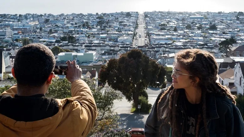 Karim taking a picture of a city with Fola looking on in The OA