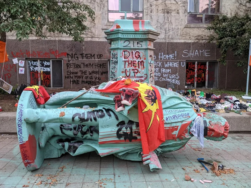The toppled statue of Egerton Ryerson, one of the architects of indigenous boarding school system, is laying on it's side in Toronto on June 6, 2021.