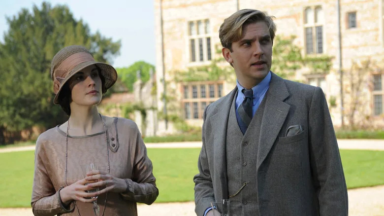 Matthew Crawley and Lady Mary standing outside in the garden drinking champagne in "Downton Abbey"