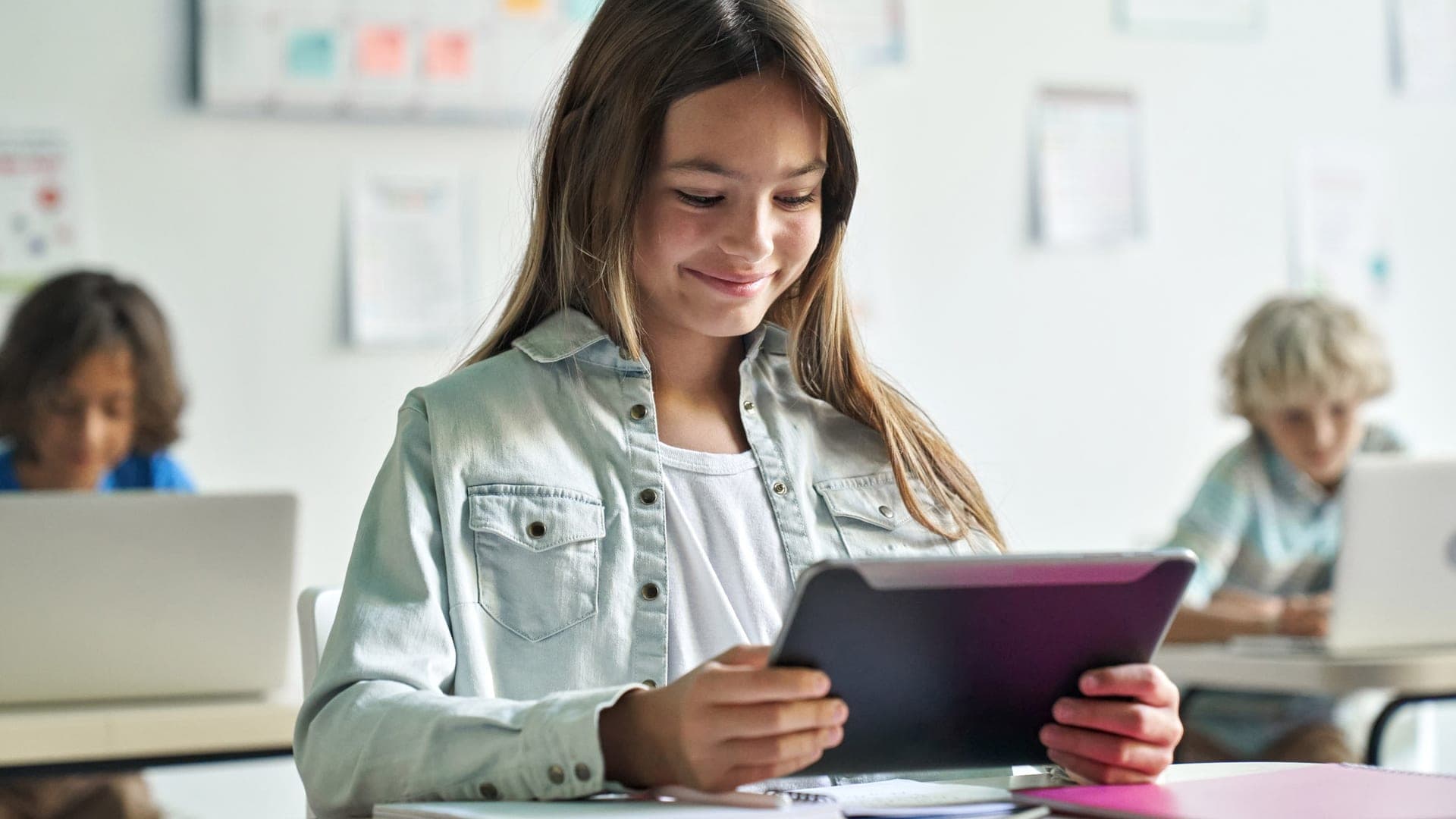 A teen student plays a game on a tablet at school.