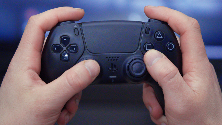 Holding a black DualSense controller with both hands