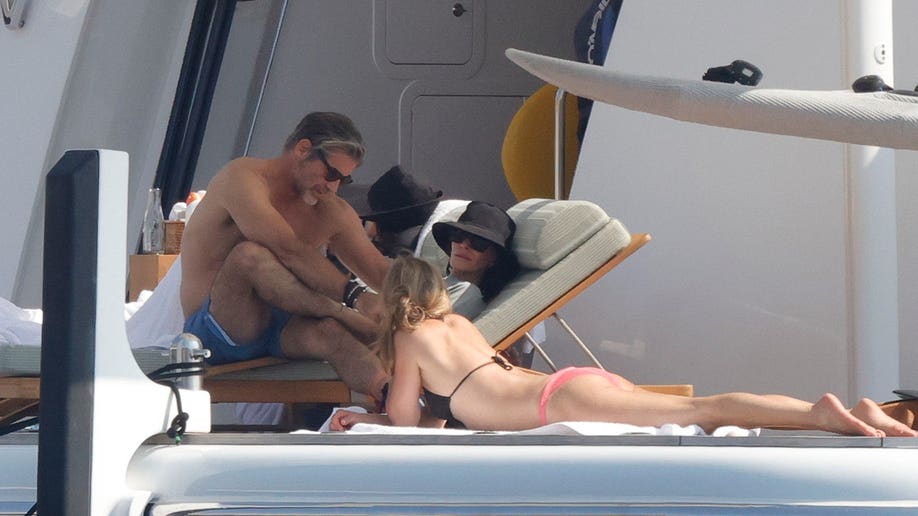 Courteney Cox, Jennifer Aniston and Jim Curtis talking while on vacation in Mallorca in July 2026.