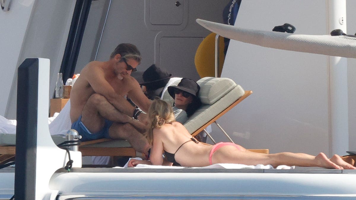Courteney Cox, Jennifer Aniston and Jim Curtis talking while on vacation in Mallorca in July 2026.