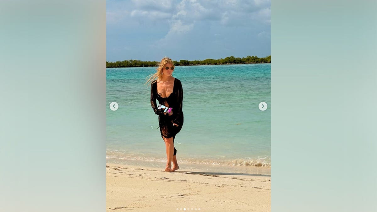 Jessica Simpson standing next to the water in a black cover-up.