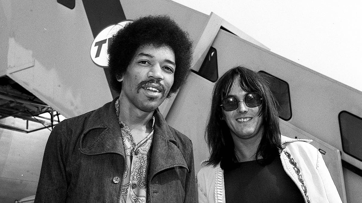 Jimi Hendrix stands with Eric Barrett at Heathrow Airport.