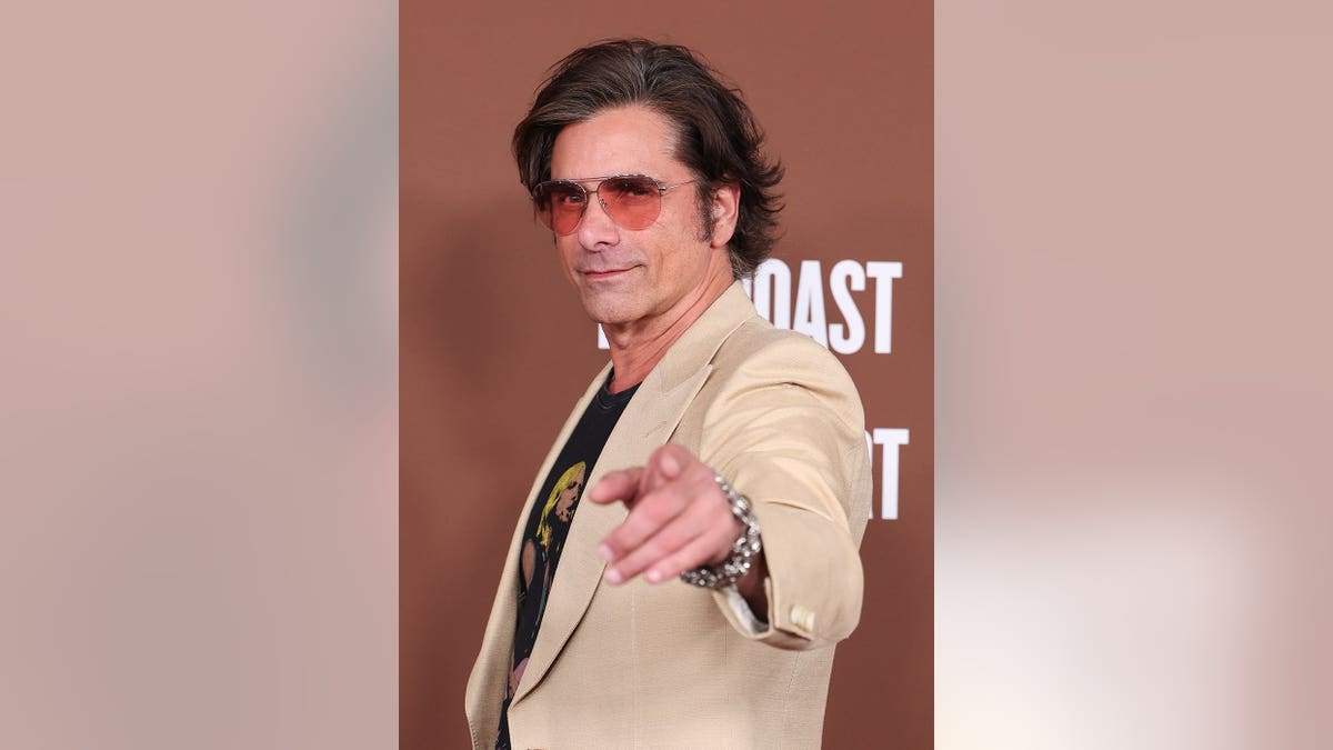 John Stamos standing on the red carpet at The Roast of Kevin Hart event