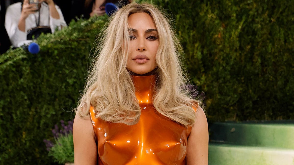 Kim Kardashian in a shiny structured orange dress at the Met Gala in New York in May 2026.