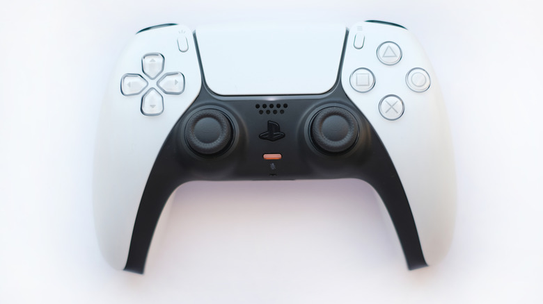 The mic mute button on a DualSense with its LED turned on, with the controller placed on a white background
