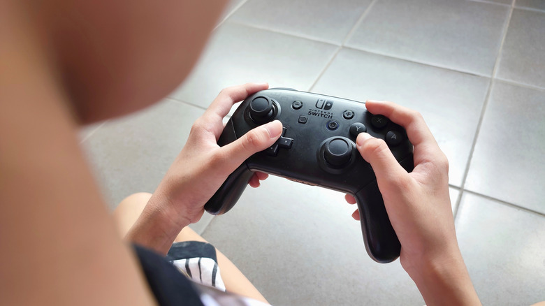 Close up of hands holding a Nintendo Switch Pro Controller