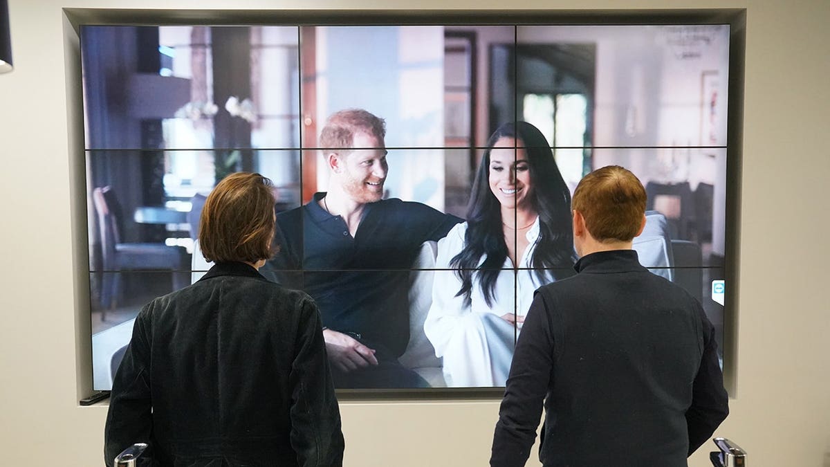 Office workers in London watch the Duke and Duchess of Sussex's documentary on a screen.