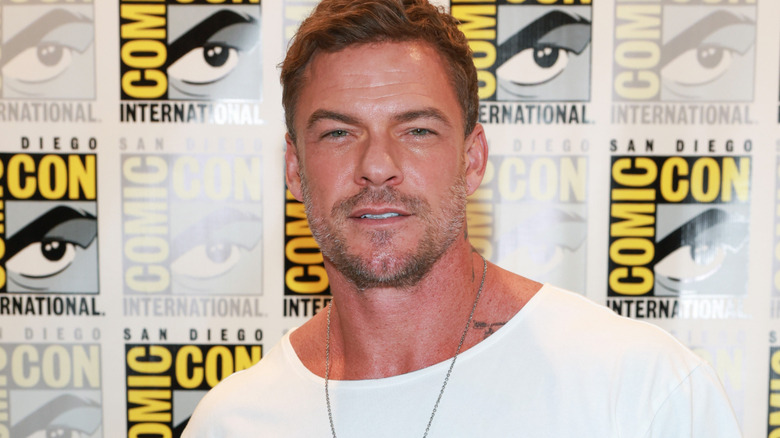 Alan Ritchson wearing white shirt at a Comic Con event